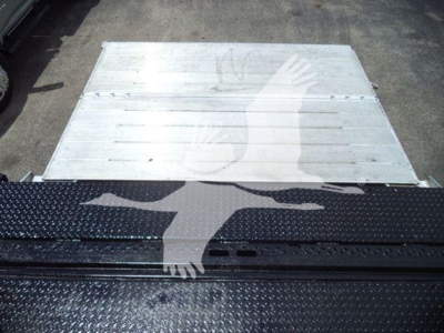 Flatbed or cargo area with metal flooring and a black textured surface featuring a graphic of two hands crossing. No legible model text visible.