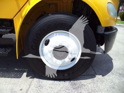 Wheel and front fender of a yellow Freightliner M2 106 truck showing a Goodyear tire and white steel wheel.