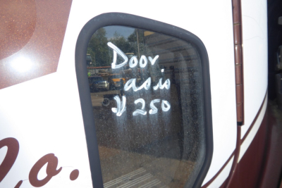 Truck cab window with handwritten white chalk/paint saying 'DOOV' or 'DOOV' and '250' on the side window, Freightliner CL112 exterior view.