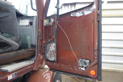 Truck cab interior rear door area showing wiring and panel with rust-like metal surface and small tail light on lower corner