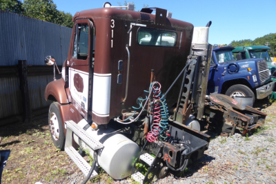 Freightliner CL112 tractor cab showing rear view with maroon/cream color, side air tanks, and exposed hoses and connectors.