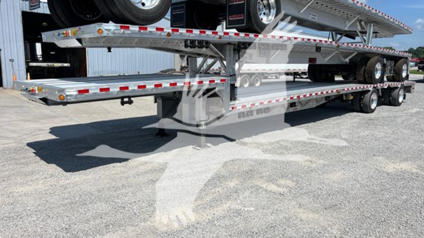 Truck trailer showing dropdeck trailer with tandem axles and reflective tape along sides.