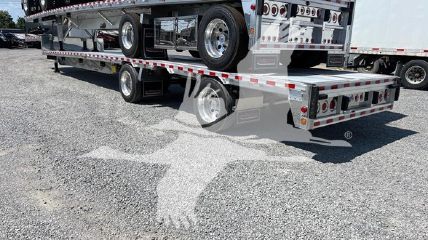 Big Bubba dropdeck trailer showing stacked flatbed deck and lower storage area with reflective tape and wheels.