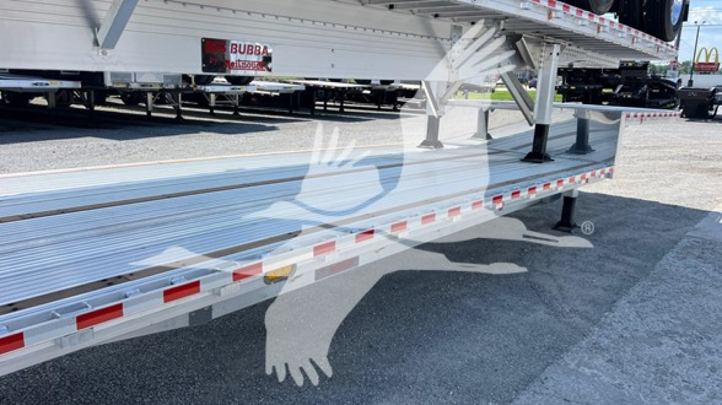 Trailer side profile showing a flatbed dropdeck with aluminum frame and reflective red/white tape along edge.