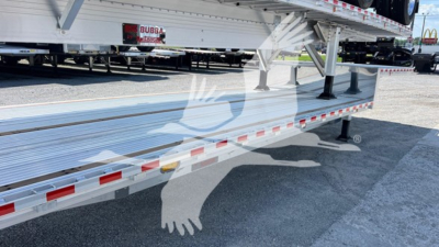 Trailer side profile showing a flatbed dropdeck with aluminum frame and reflective red/white tape along edge.