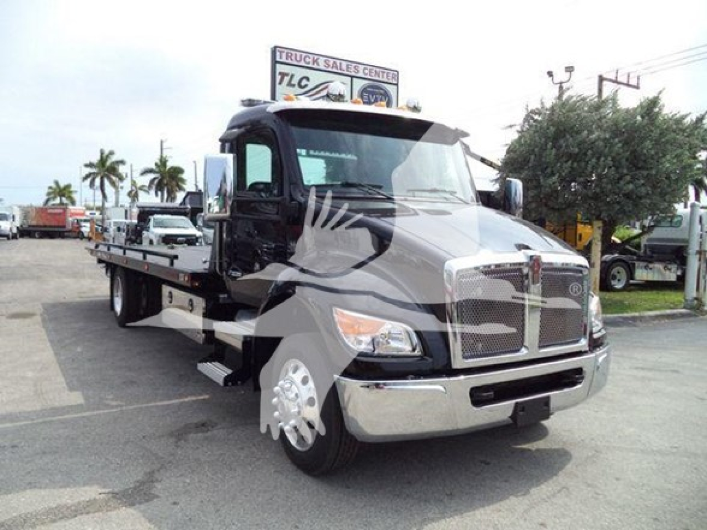 Kenworth T680/like tow truck in a rollback configuration with flatbed and chrome grille; cab with black and chrome accents, side mirrors, and front bumper.