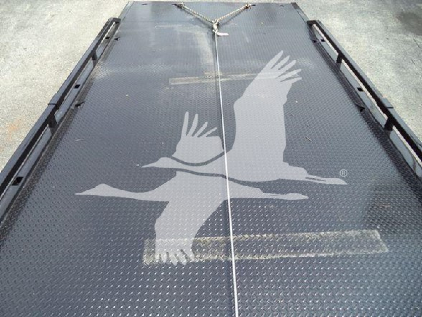 Kenworth T280 rollback truck deck showing textured metal surface with white birds graphic and chain tie-downs.