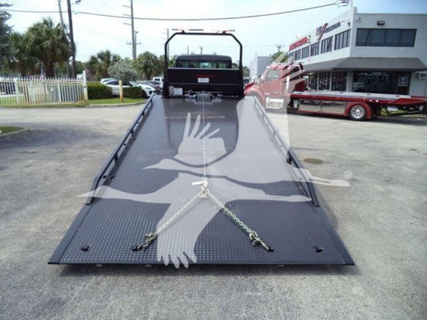 Kenworth T280 rollback truck flatbed viewed from rear with diamond plate steel bed and chains securing across the ramp.