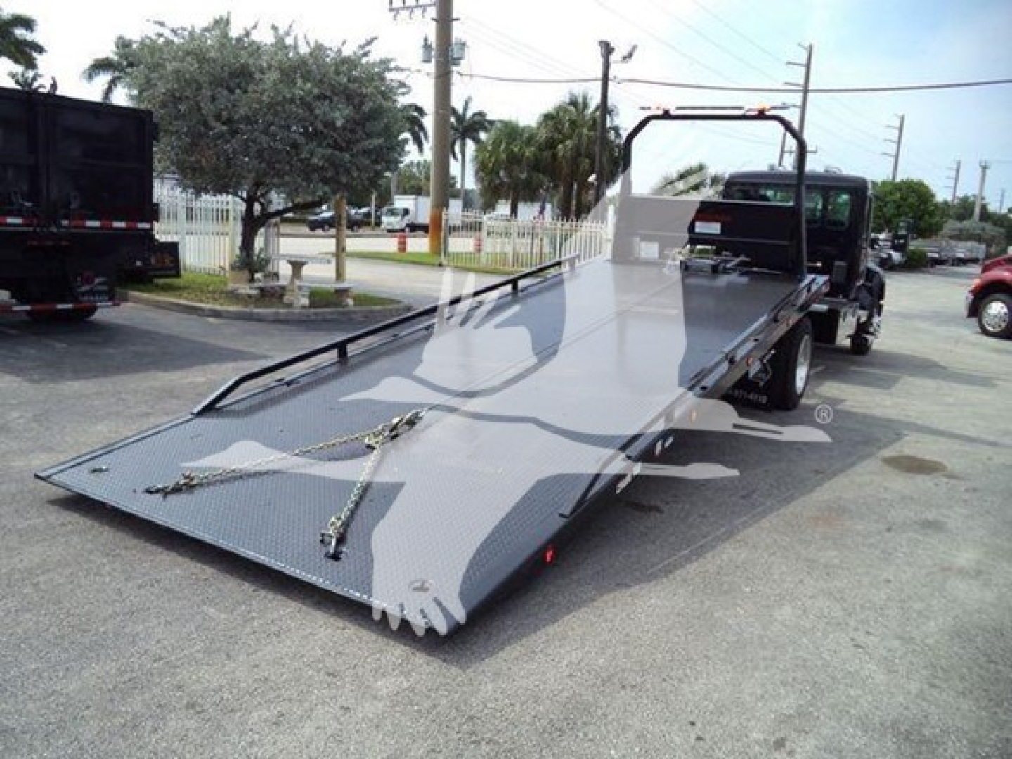 Kenworth T280 rollback truck with flatbed in lowered position showing ramps, side rails, and hook points.