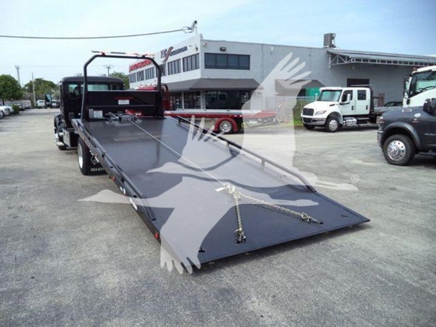 Kenworth T280 rollback flatbed truck in a dealership lot with ramp extended, VIN 2NK3HM6XXSM140823, stock J40823.