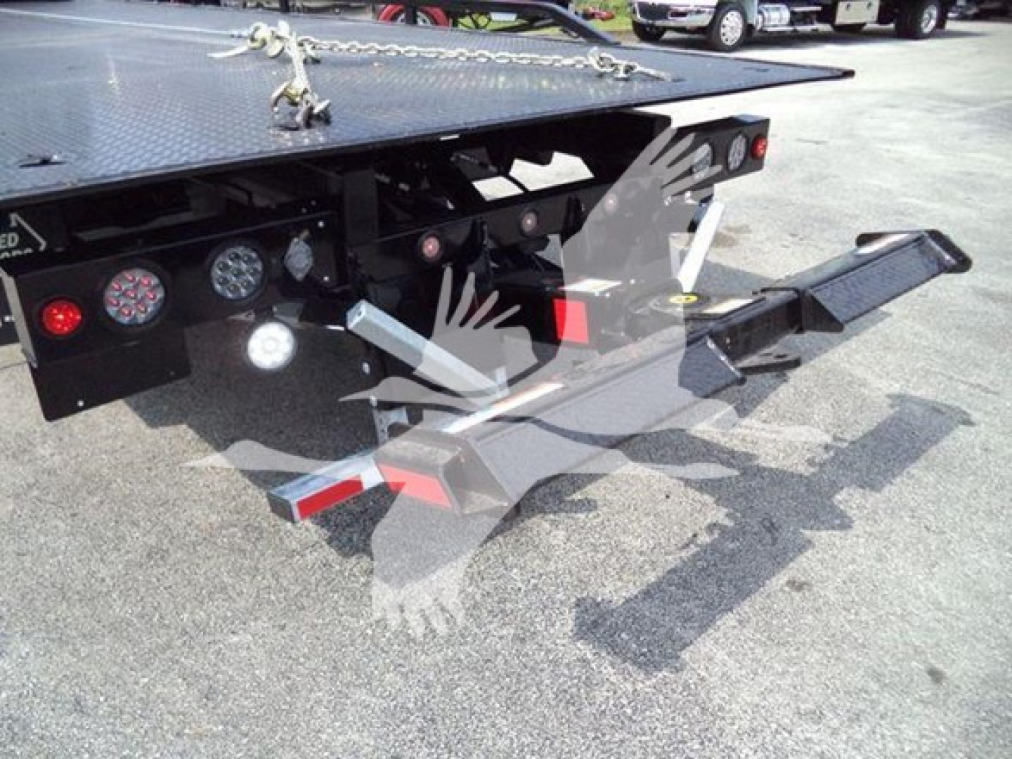 Back of a rollback tow truck with a hydraulic wheel lift and ramp, rearview showing LED lights and warning decals.