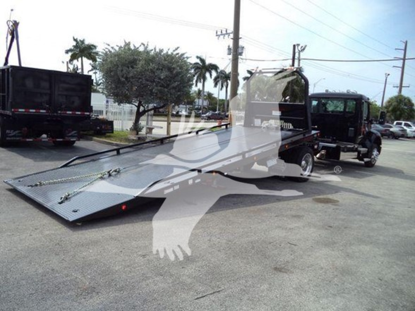 Kenworth T280 rollback tow truck with flatbed in driveway showing front and side view, vehicles and palm trees in background.