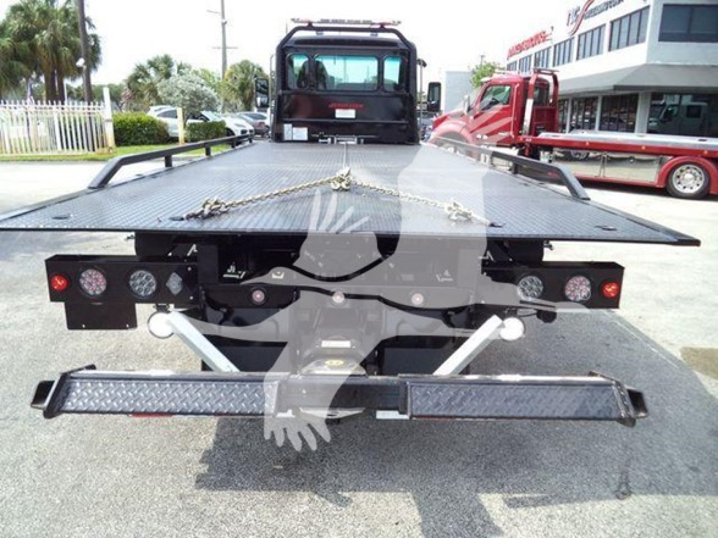 Kenworth T280 rollback flatbed showing rear view with loading ramp and winch points, taillights, and diamond plate bed.