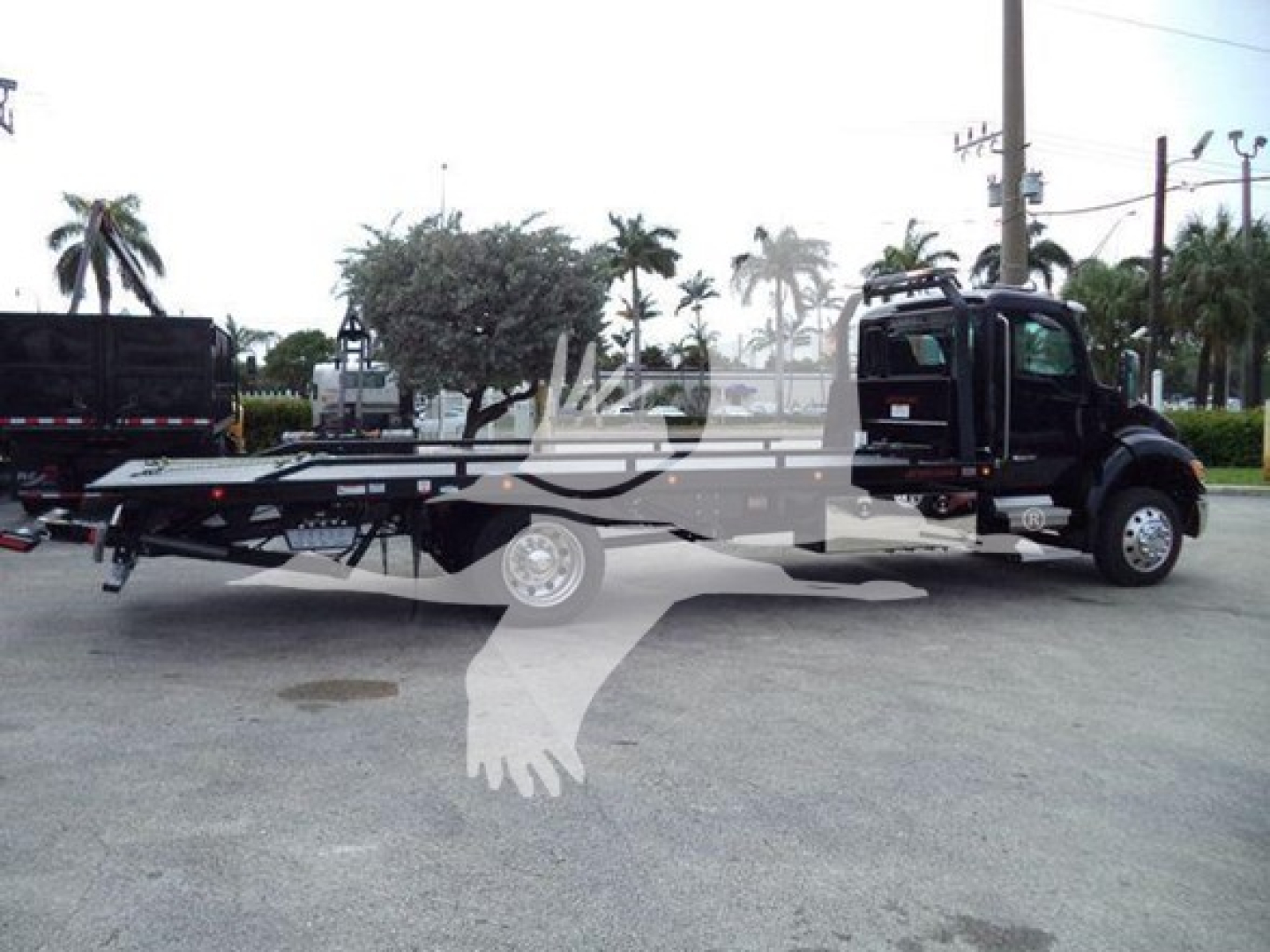 Kenworth T280 rollback truck on lot side view showing wheelbase and long flatbed with towing equipment.