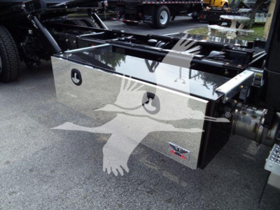 Kenworth rollback truck bed toolbox with polished metal toolbox showing John Deere logo? No, image shows chrome toolbox on truck chassis with reflective surface and a decal of a white bird in flight overlaying.