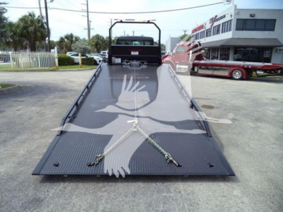 Kenworth T280 rollback truck flatbed viewed from rear with diamond plate steel bed and chains securing across the ramp.