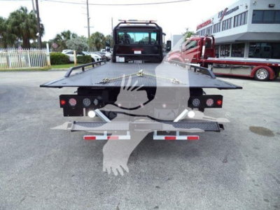 Rear view of a 2025 Kenworth T280 rollback tow truck showing flatbed loading deck, taillights, and bumper with reflectors.