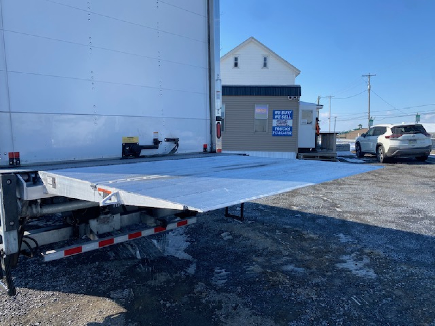 Freightliner M2 106 flatbed truck rear view showing aluminum ramp and trailer hitch area.