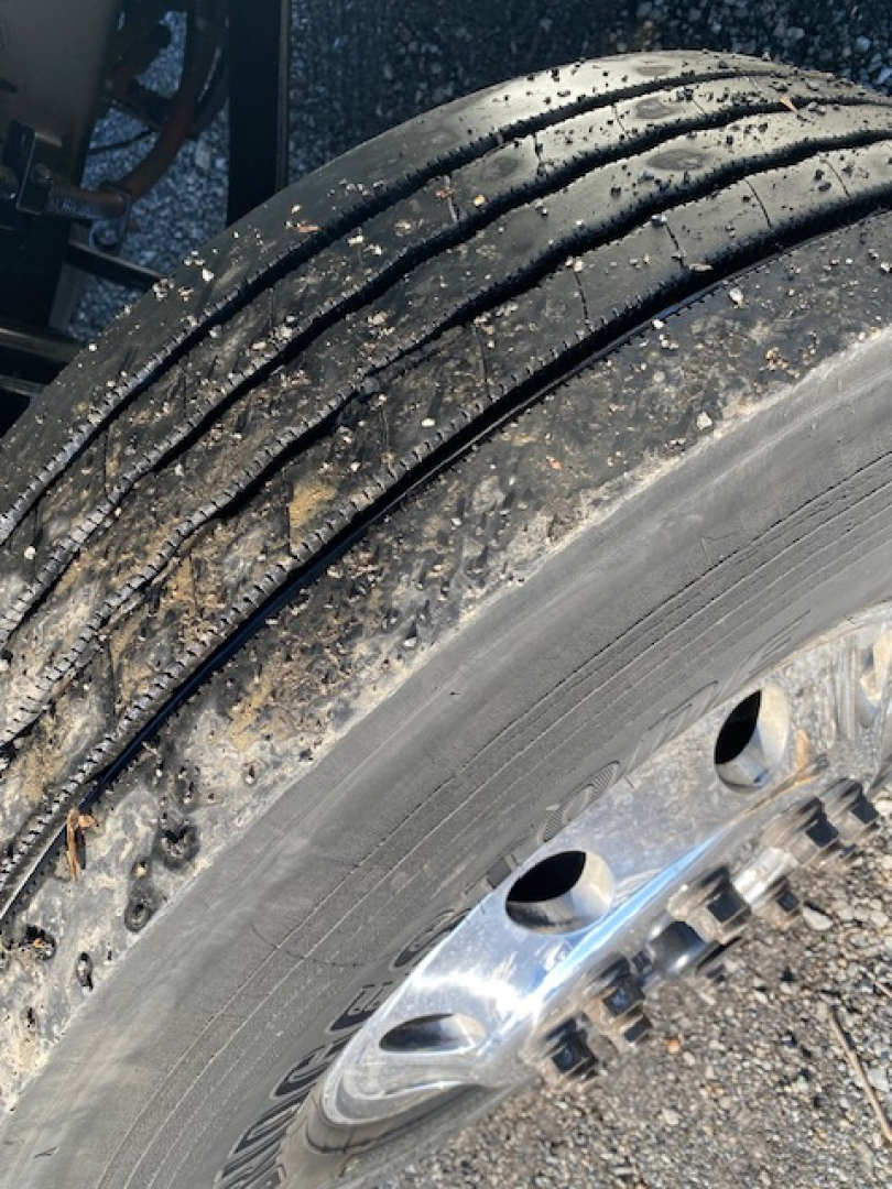 Tire and wheel close-up on Freightliner M2 106 truck showing dual tread with mud and wheel hub