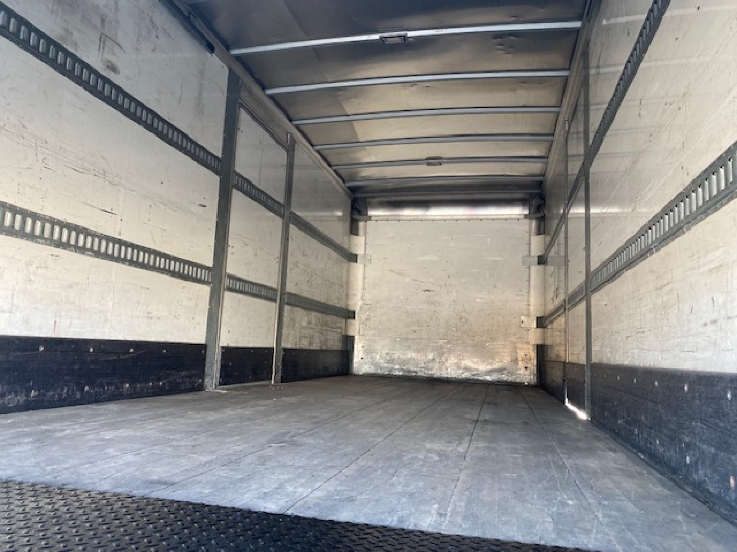 Freightliner M2 106 truck box interior empty cargo area with metal side rails and wooden floor, long rectangular trailer.