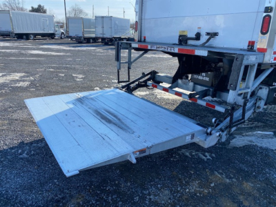 Freightliner M2 106 rear loading ramp extended showing aluminum fold-out lift gate and truck bed with hydraulic mechanism and reflective tape.