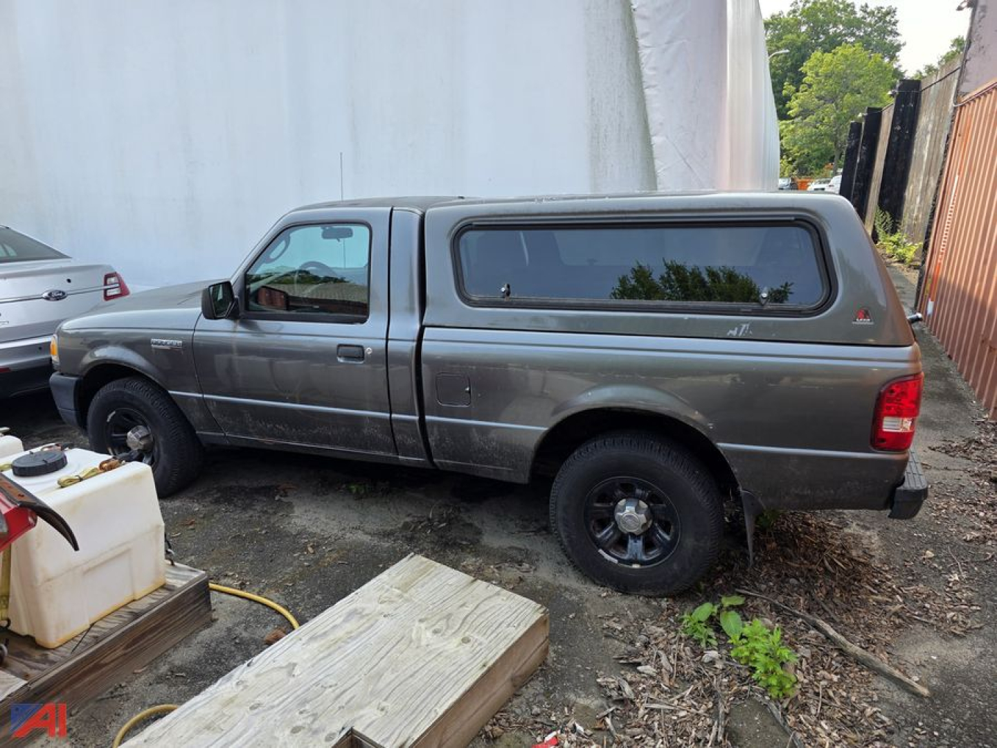 Ford Ranger pickup truck with cap side view showing gray body and black 4x4 cap window.