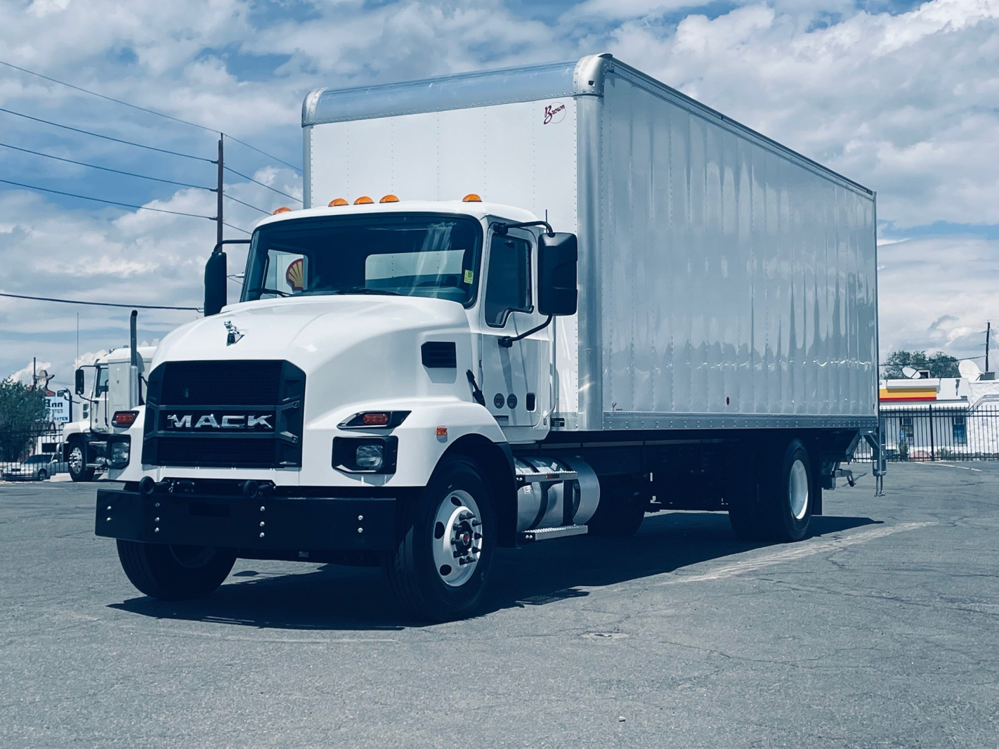 Box truck front three-quarter view showing 2026 Mack MD6 with white cab and large box body, VIN 1M2MDBAA2TS018612 visible in listing context.