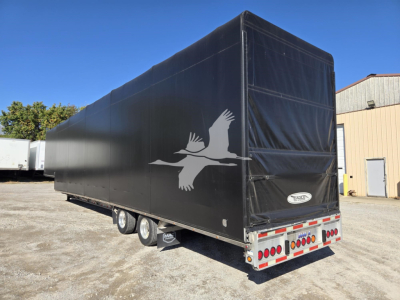 Drop deck trailer with black tarp featuring white bird silhouette, rear view showing lights and bumper.