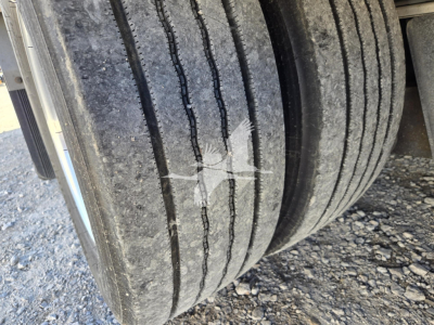 Vehicle trailer wheel and dual tires showing tread pattern and wear lines on the outermost tires.