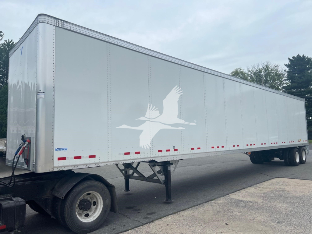 Vanguard VXP trailer showing long silver cargo body with white gull logo and lower red/white reflective markers.