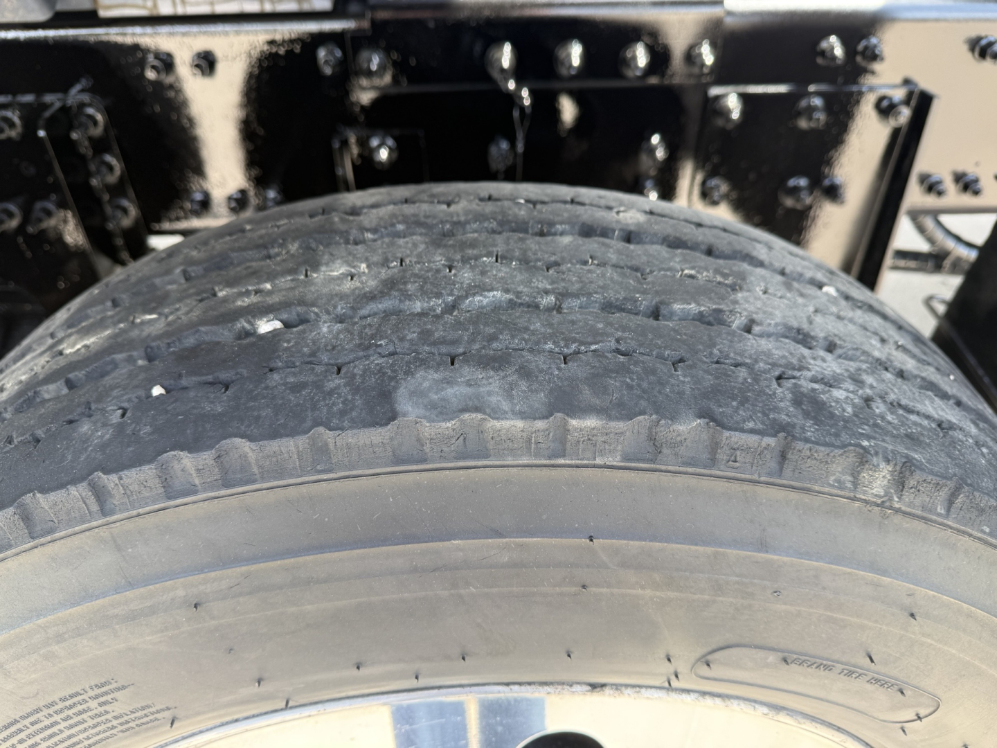 Truck wheel and tire close-up undercarriage showing tread wear and mechanical frame.