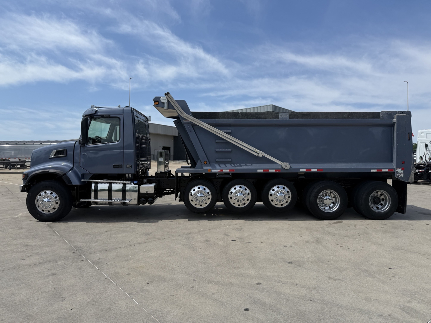 Volvo VHD truck, side view, dump body, eight-wheel rear tandem configuration, with hydraulic dump hoist and dark gray body.