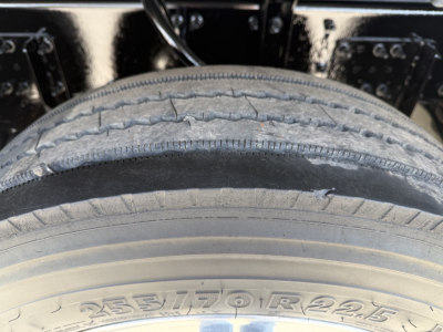 Tire with visible tire size marking 255/70 R 22.5 on the sidewall along with part of the truck chassis and wheel.
