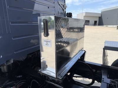 Truck VIN 4V5KJ9EH3RN652474 used dump truck with diamond plate tool/storage box mounted on side, hydraulic oil label, visible wheel and chassis components.
