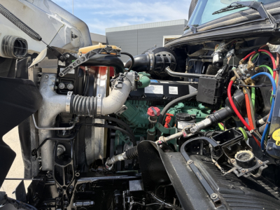 Volvo VHD104F300 dump truck engine bay showing multiple hoses, wiring, and components with exposed engine area.
