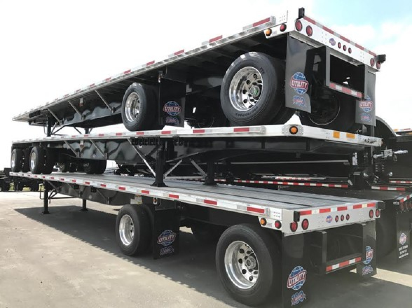 Utility 4000Ae combo flatbed trailer stacked on trailer with spare tires and reflective tape.