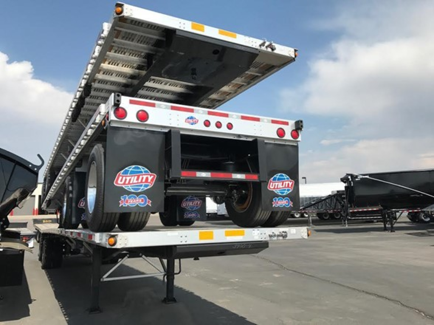 Utility 4000Ae combo flatbed trailer viewed from rear with drop-down ramp raised, dual rear axles, and spare tires mounted under the deck.