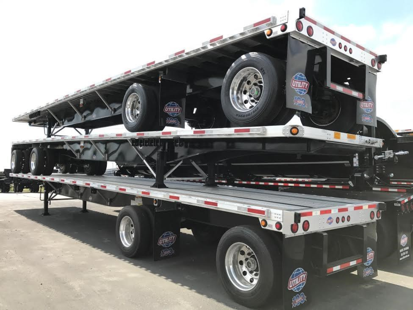 Trailer showing stacked flatbed trailers with wheels, Utility logo, and reflective tape on aluminum framing.