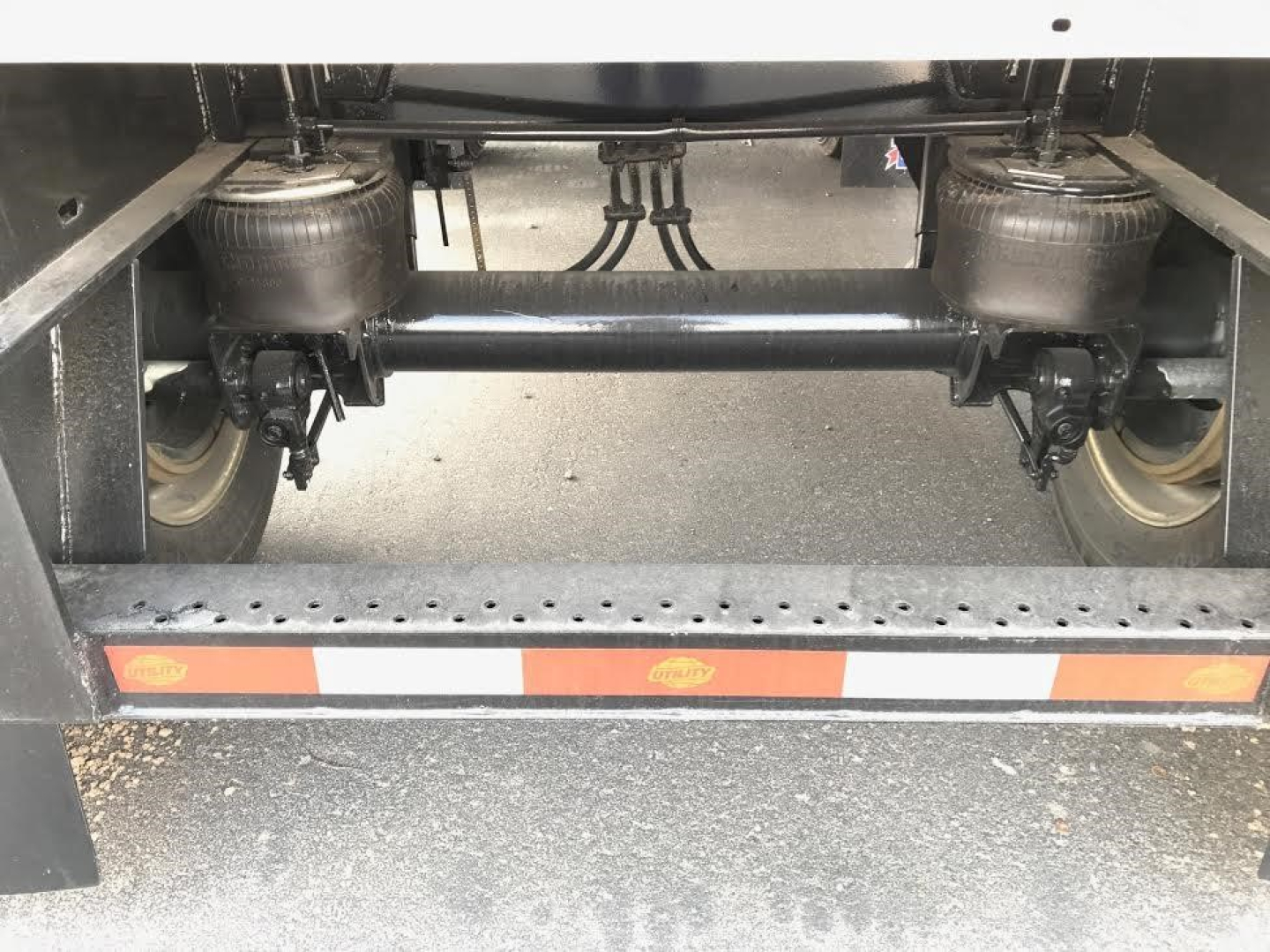 Trailer undercarriage showing tandem axles and suspension components on a flatbed trailer.