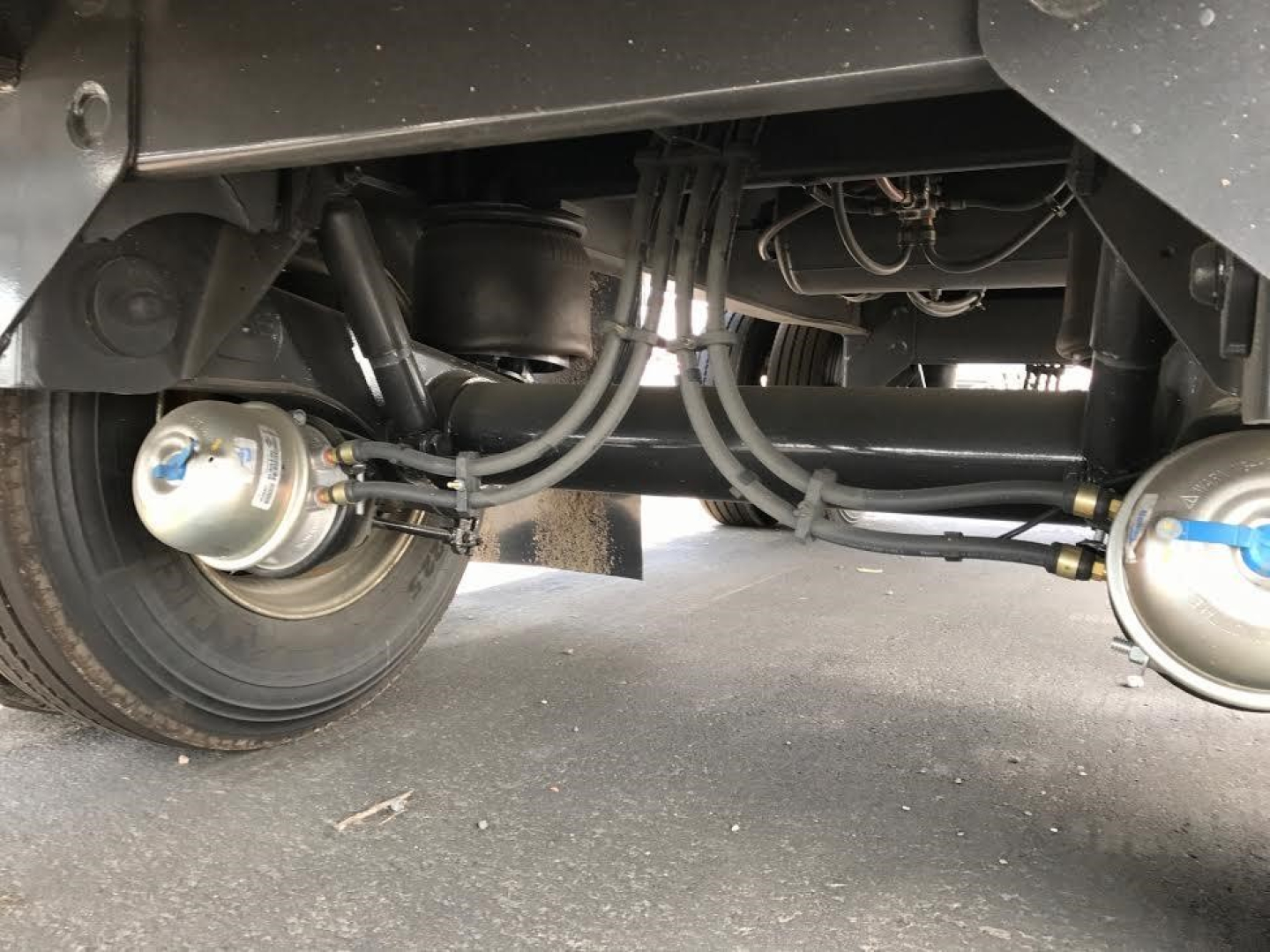 Utility 4000AE trailer underside showing axles, air brake lines, suspension, and tanks with hoses and fittings visible.