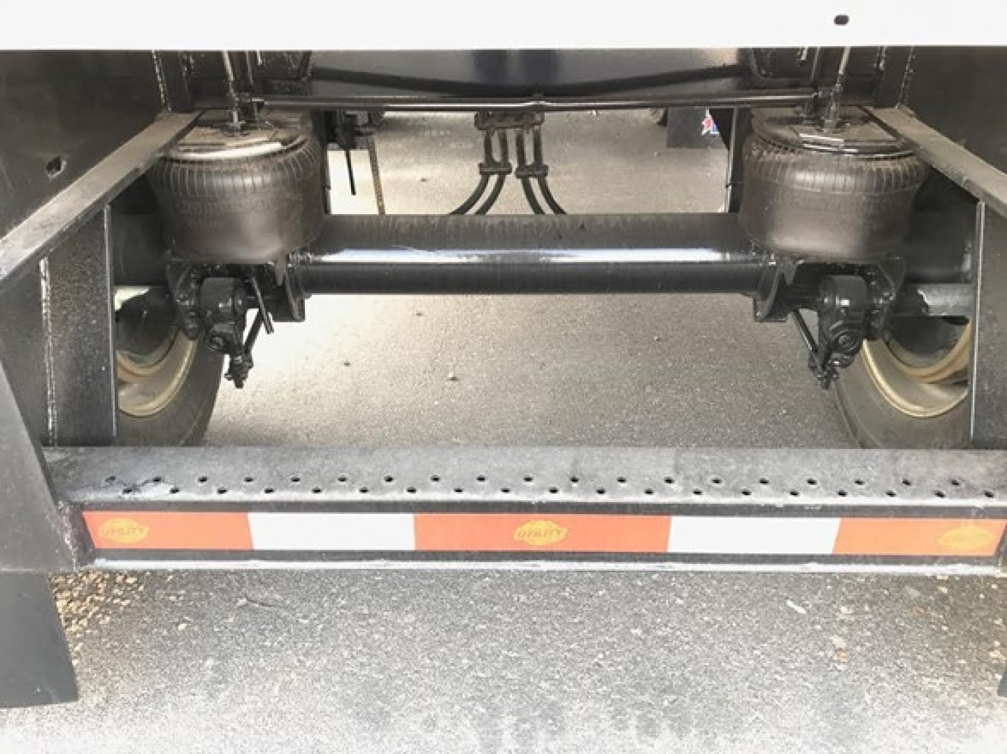 Utility trailer undercarriage showing dual air ride suspension with compressors and wheels, rear frame with reflective tape.