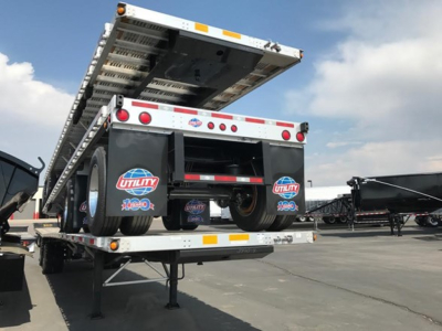 Utility 4000Ae combo flatbed trailer viewed from rear, lifted ramp with underside components visible, Utility brand logos on mud flaps, multiple tail lights, tandem axle.