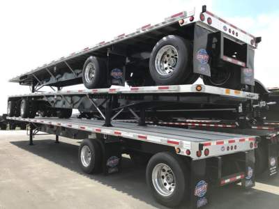 Trailer showing stacked flatbed trailers with wheels, Utility logo, and reflective tape on aluminum framing.