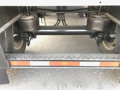 Trailer undercarriage showing tandem axles and suspension components on a flatbed trailer.