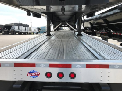 Flatbed trailer bed with metal decking and rear lights showing Utility logo, undercarriage framework visible.