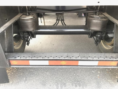 Utility trailer undercarriage showing dual air ride suspension with compressors and wheels, rear frame with reflective tape.