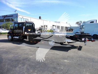 Tow truck flatbed rollback showing International MV truck in black with extended flatbed and towing equipment.