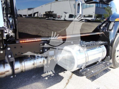 Truck side view showing cylindrical chrome fuel tank and side step under the door and a portion of the cab.