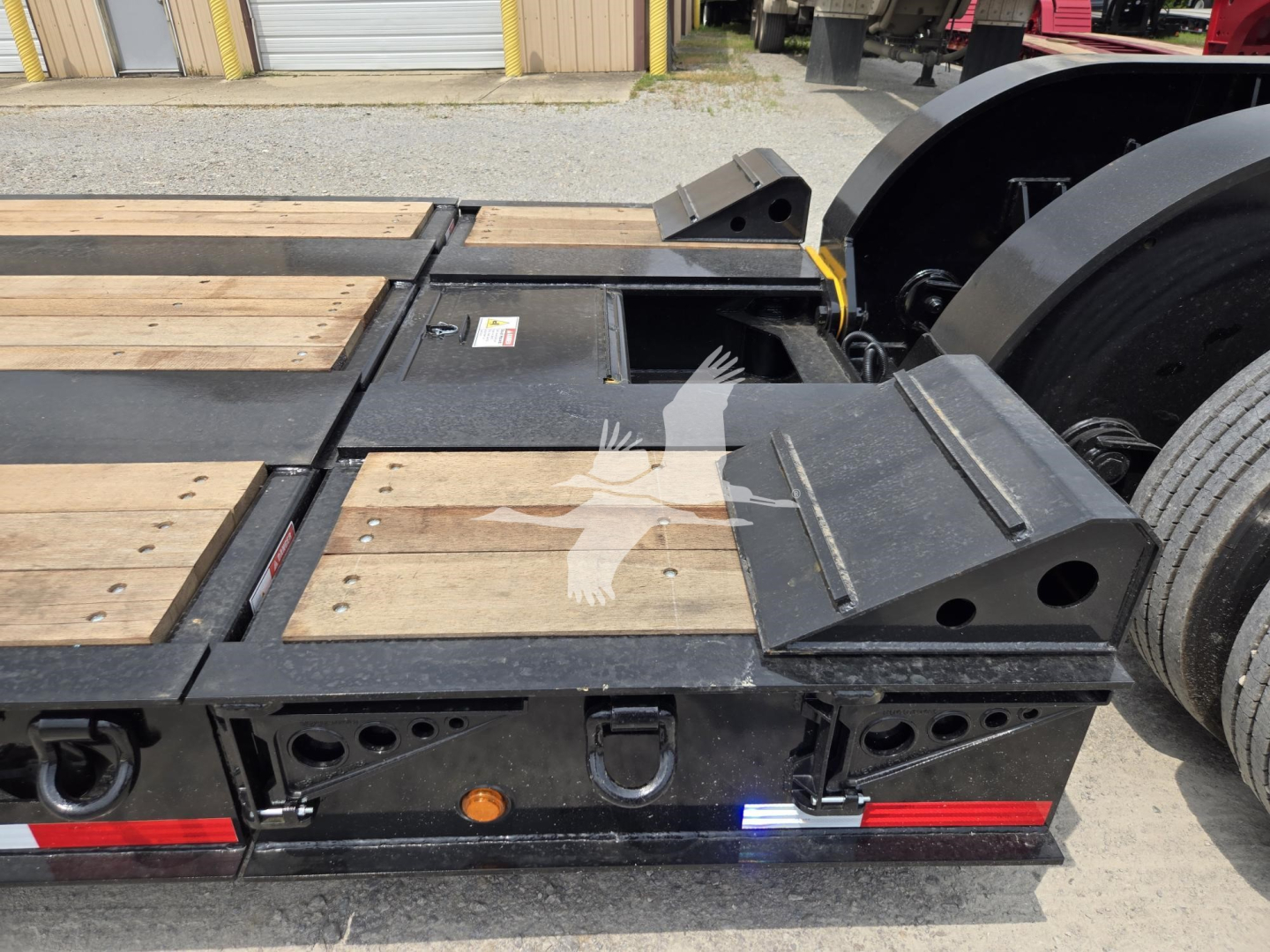 Fontaine 60Hd MX lowboy trailer rear deck with wooden planks, ramps, and bumper lights; visible VIN and stock info not on image; metal components and labels visible.