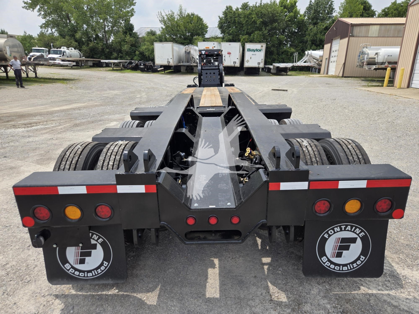 Trailer rear view showing 60ft lowboy with dual axle and heavy-duty frame, taillights, mudflaps with Fontaine Specialties logo, and rear bumper with reflectors.